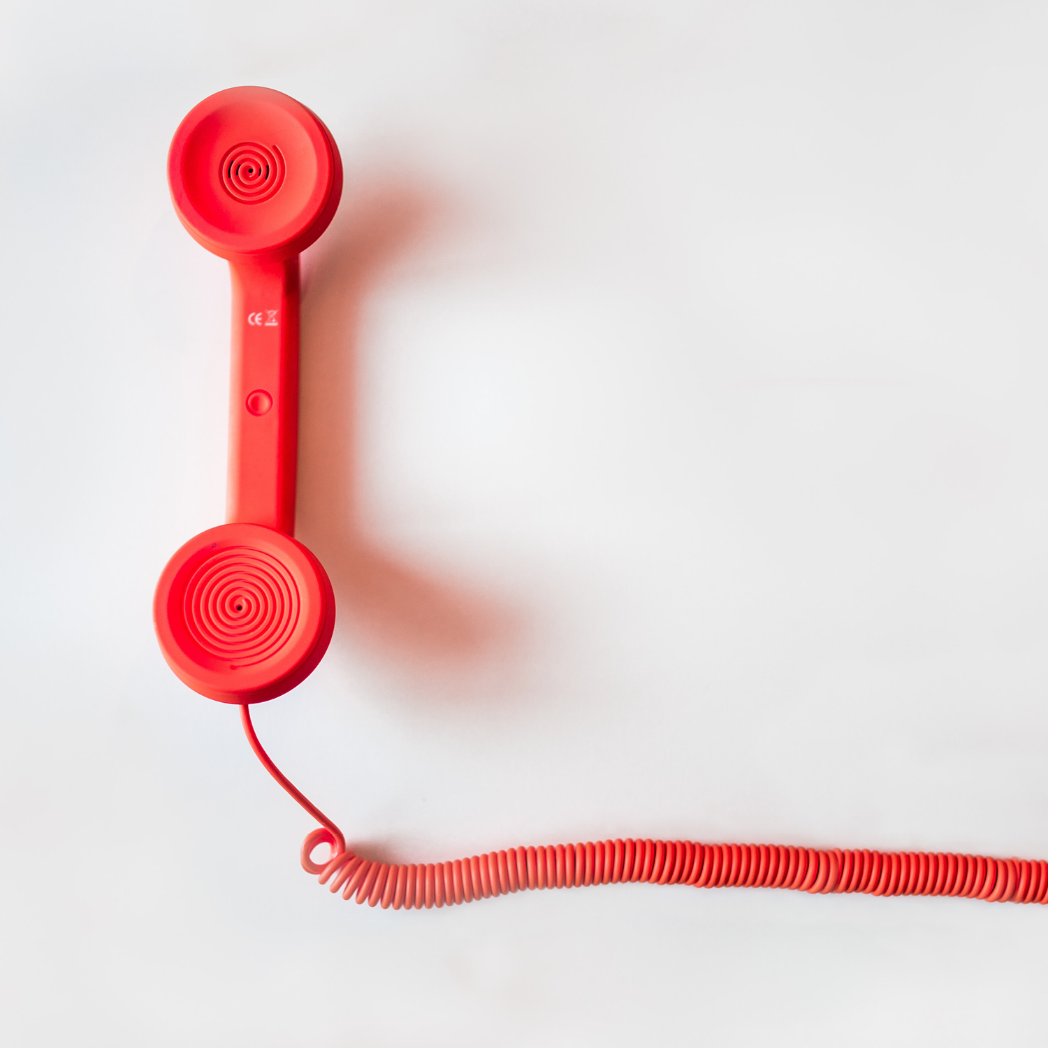 An old fashioned red telephone handset and cord.