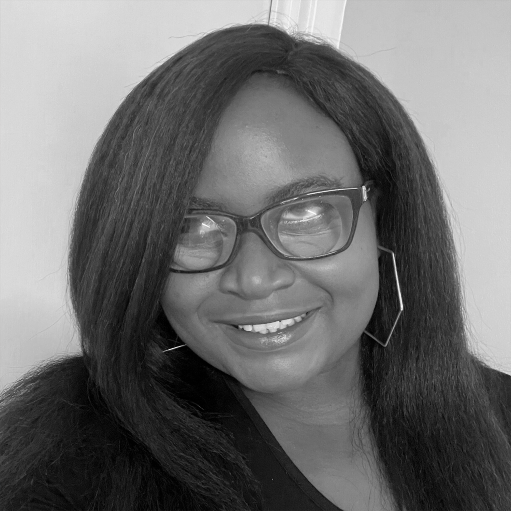 A young black woman with shoulder length hair, glasses and hoop earings.