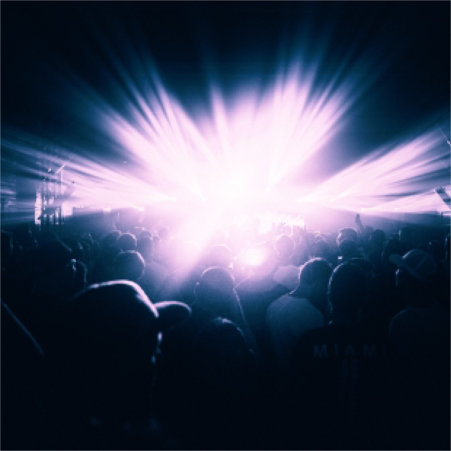 A crowd in a dark venue lit by a bright white light