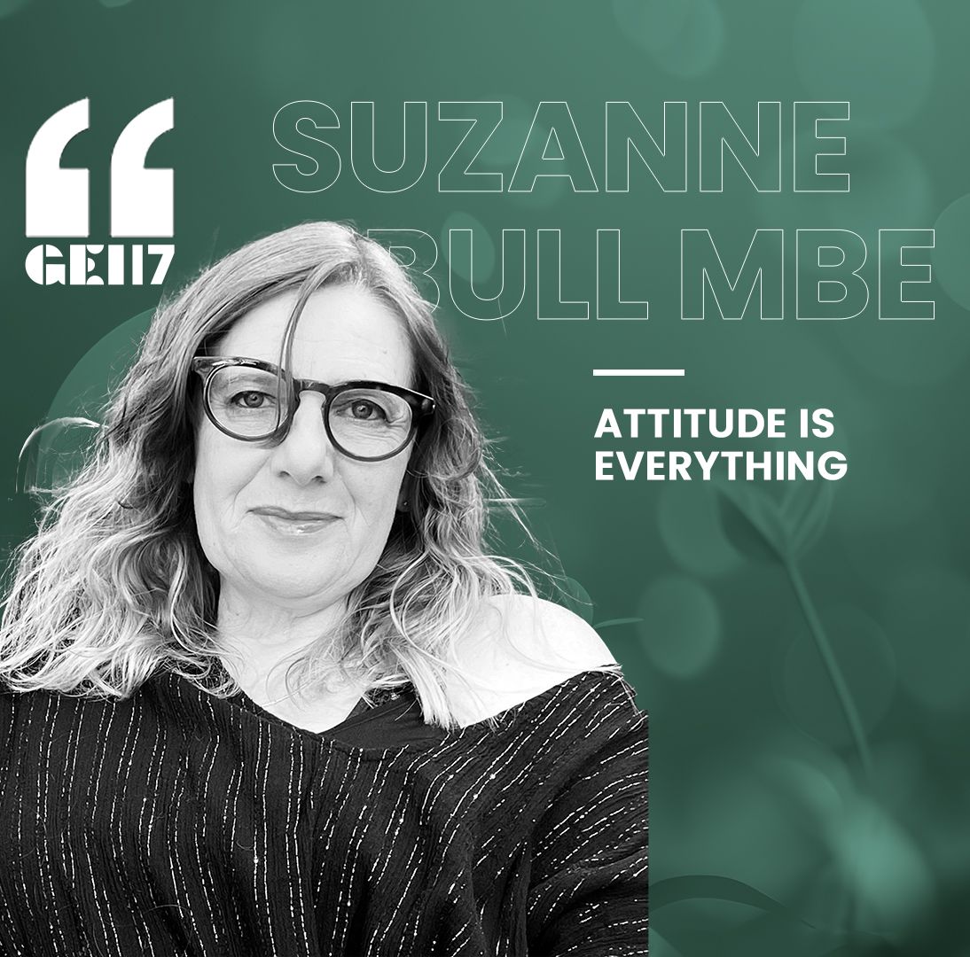 Black and white headshot of Suzanne Bull MBE, founder of Attitude is Everything, with GEI17 branding. Suzanne is a white woman with long curly hair, glasses, and is wearing a glittery top.